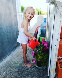 Portrait of happy girl standing by flowering plants