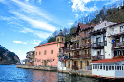 Buildings by river against sky