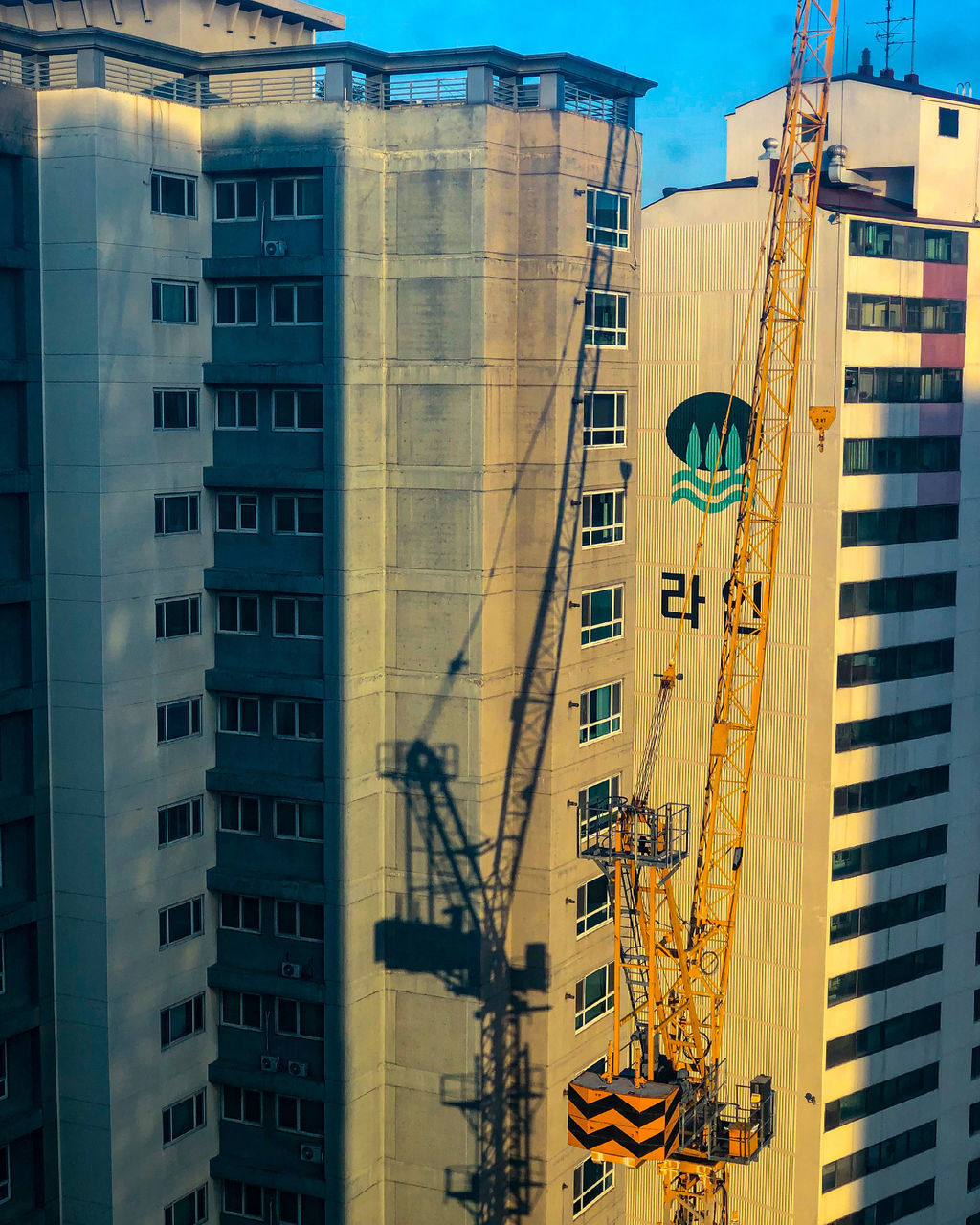 LOW ANGLE VIEW OF CRANE BY BUILDINGS IN CITY