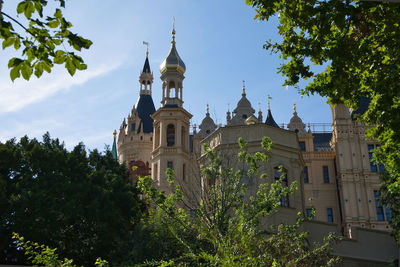 Low angle view of trees and building against sky