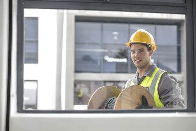 Portrait of construction worker carrying cable drum