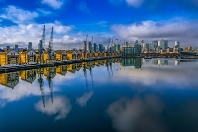 Bridge over river by buildings against sky in city