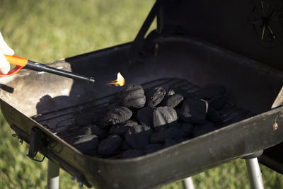 Cropped hand igniting barbecue grill