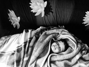 High angle view of toddler wrapped in blanket sleeping on sofa at home