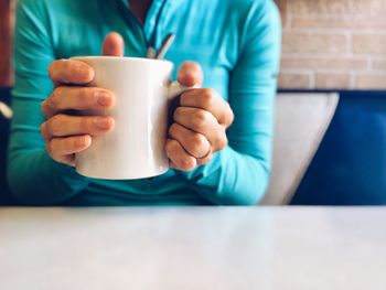 Midsection of man holding coffee cup