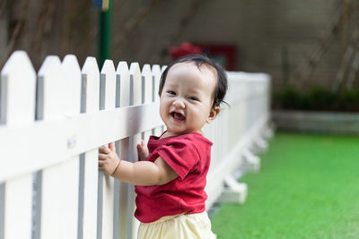 Portrait of cute girl smiling by fence