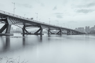 Bridge over river against sky in city