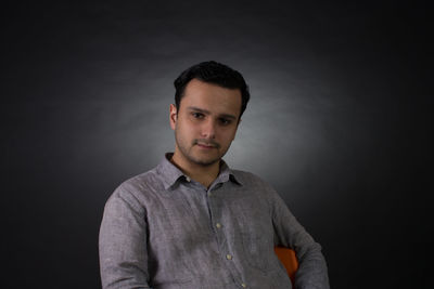 Portrait of confident young man against gray background