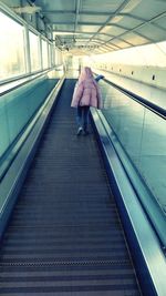 Rear view of woman walking on escalator