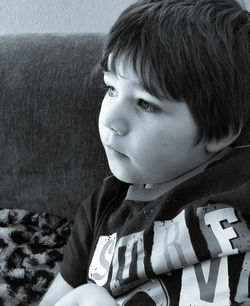 Close-up of cute girl sitting on sofa at home