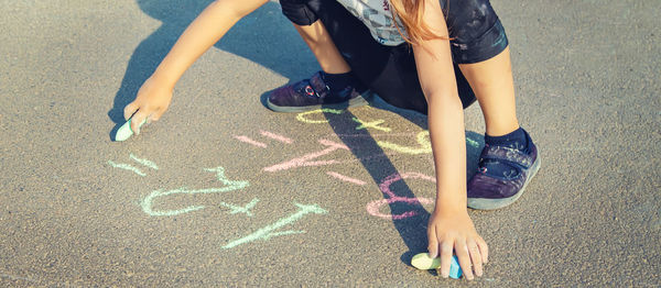 Low section of boy writing with chalk on road