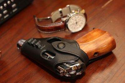 High angle view of gun with wristwatch on table