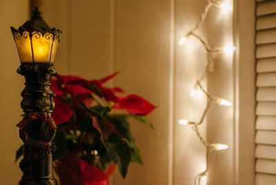 Close-up of illuminated lamp hanging against wall at home