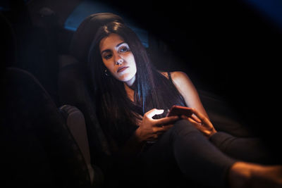 Young woman using smart phone sitting in darkroom