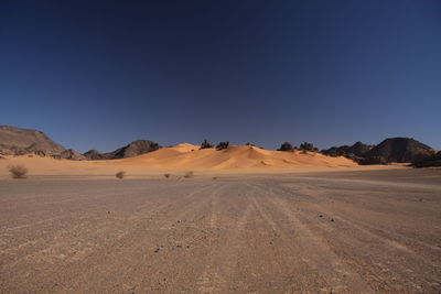 Scenic view of desert against clear blue sky red dune, akakus mountain, libya