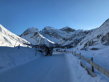 Scenic view of snow covered mountains against clear blue sky
