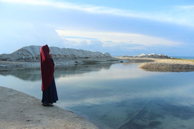 Rear view of man standing on beach against sky