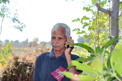  farmer or gardener standing in a field talking to an agricultural  specialist on a keypad mobile