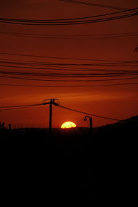 Silhouette electricity pylon against sky during sunset