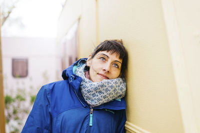 Front view of a smiling woman standing outdoors while looking away