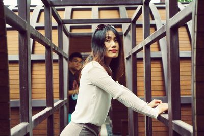 Portrait of young woman standing against railing