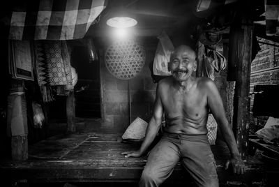 Portrait of shirtless man standing in illuminated room