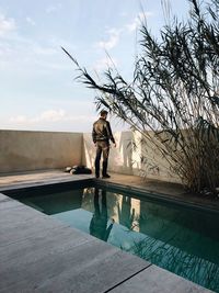 Man standing by swimming pool against sky