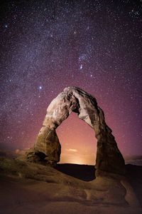 Low angle view of natural arch against star field at arches national park