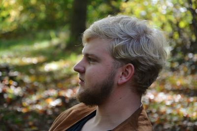 Profile view of young man against trees