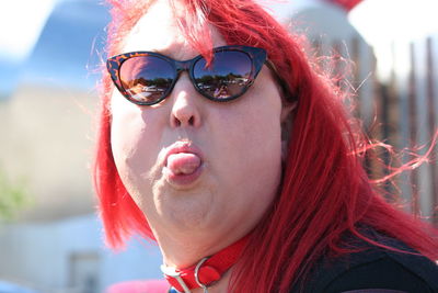 Redhead woman sticking out tongue outdoors