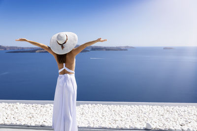 Rear view of woman standing by sea against sky