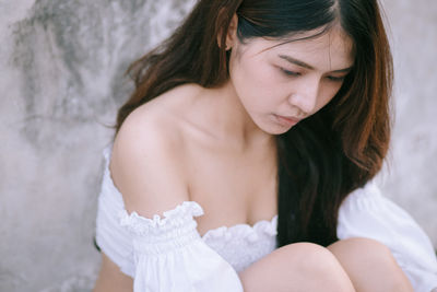 Midsection of woman looking down while sitting on bed