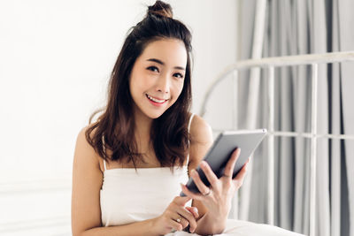 Portrait of smiling young woman using mobile phone