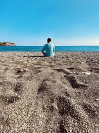 Rear view of man looking at sea against clear sky