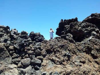 Rear view of woman standing on rock against sky