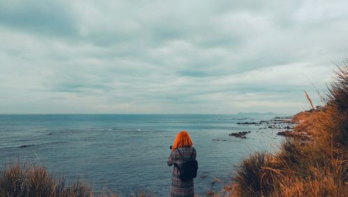 Rear view of woman standing against sea at beach