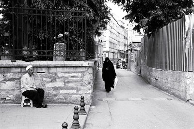 Rear view of people walking on footpath in city