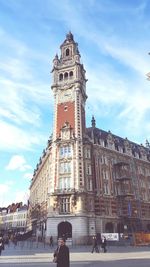 Low angle view of clock tower against cloudy sky