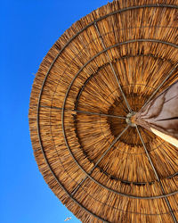 Low angle view of parasol against clear blue sky