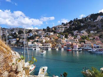 Sailboats moored on sea by buildings in city against sky