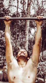 Portrait of young man with arms raised in park