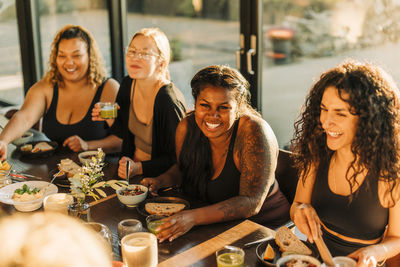 Happy female friends enjoying breakfast together at retreat center