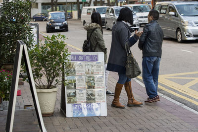 Rear view of people walking on street in city