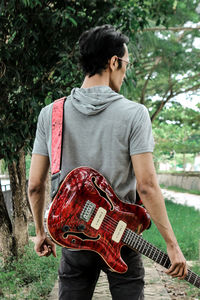 Rear view of man holding guitar
