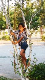 Portrait of smiling young woman standing against tree