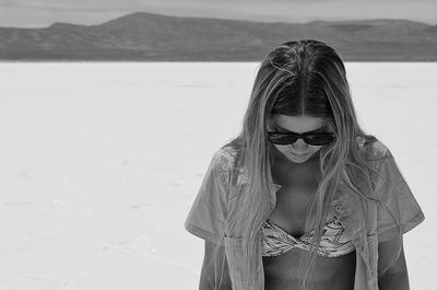 Young woman wearing sunglasses standing on beach