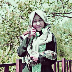 Portrait of smiling young woman standing against trees