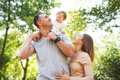 Father and son holding baby while standing outdoors
