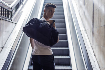 Side view of young man standing against building