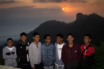 Portrait of friends standing on mountain against sky